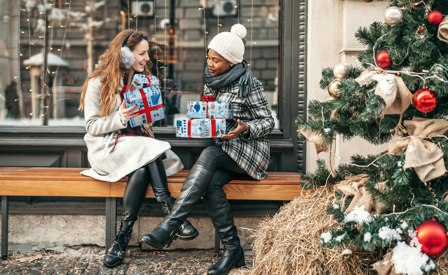 Deux femmes s’échangent des cadeaux devant un magasin.
